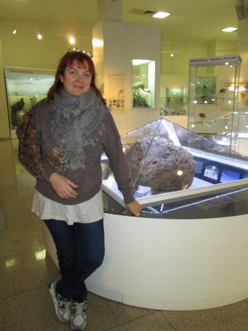 Dum la ekskurso en Ĉelabinska muzeo post la EsPrimo 11, en 2015.  Katerina kun la bandaĝita mano apud la montrofenestro kun la fragmento de la ĉelabinska meteorito